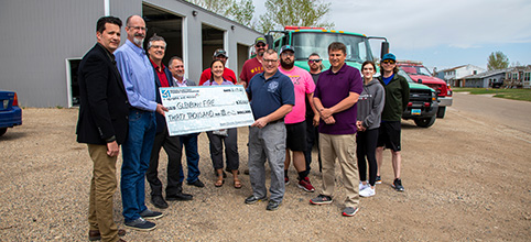 Group of employees outside with large donation check