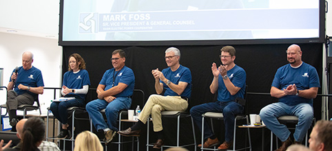 Executive team in matching blue tshirts sitting on high top stools