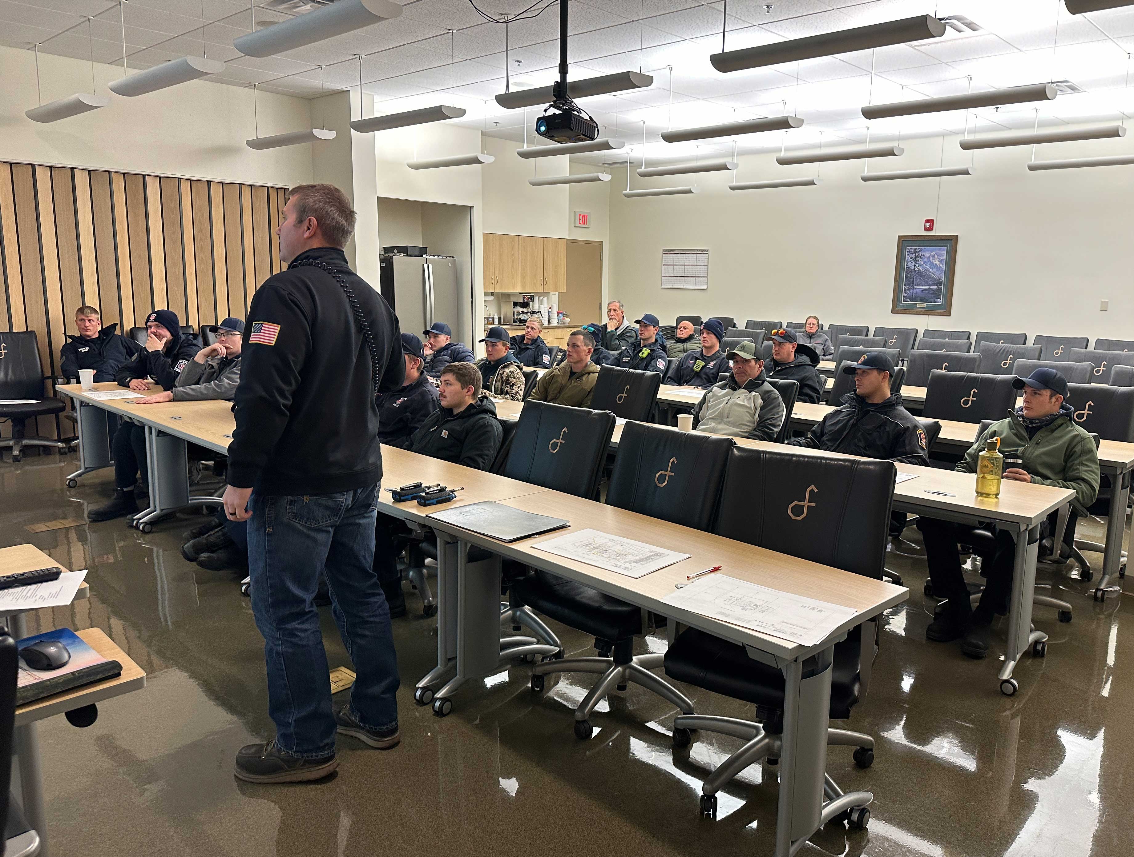 Man instructs group of firefighters in a classroom